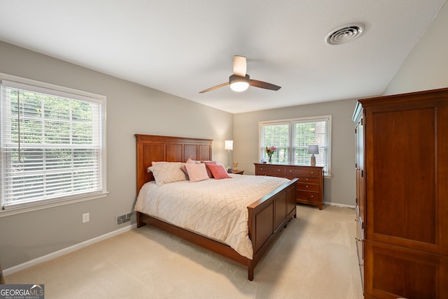 bedroom featuring light colored carpet, baseboards, and a ceiling fan