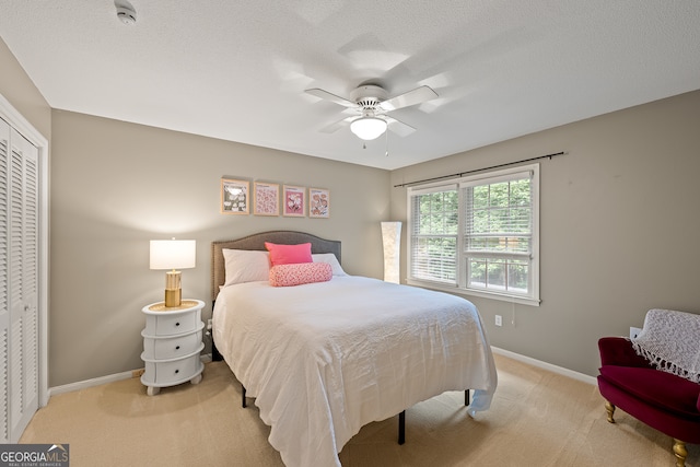 bedroom with baseboards, light carpet, a closet, and ceiling fan