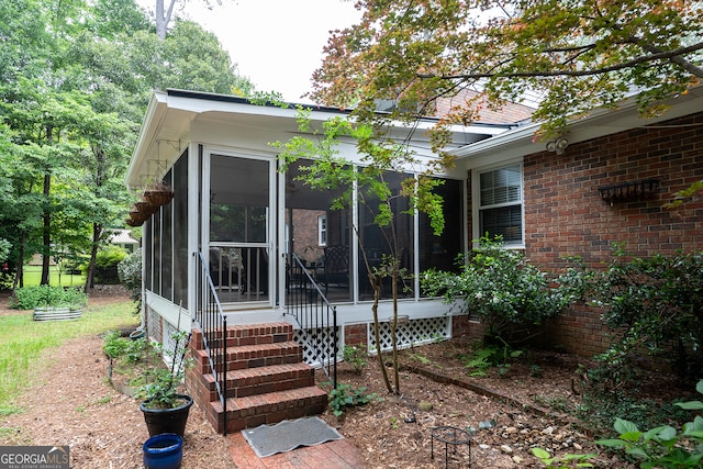 rear view of property featuring a sunroom and brick siding