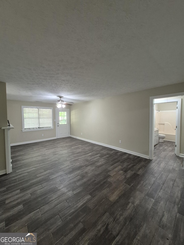 unfurnished living room featuring dark wood-type flooring, ceiling fan, baseboards, and a textured ceiling