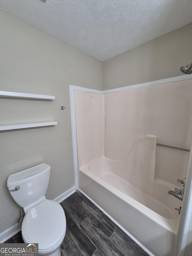 full bathroom featuring a textured ceiling, toilet, baseboards, wood finished floors, and shower / bathtub combination