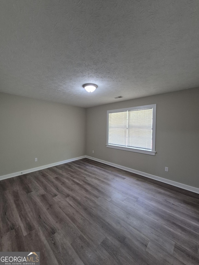 empty room featuring dark wood finished floors, baseboards, and a textured ceiling