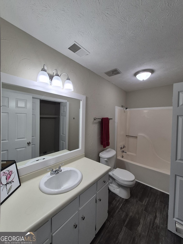 full bath featuring wood finished floors, a textured ceiling, bathing tub / shower combination, toilet, and vanity