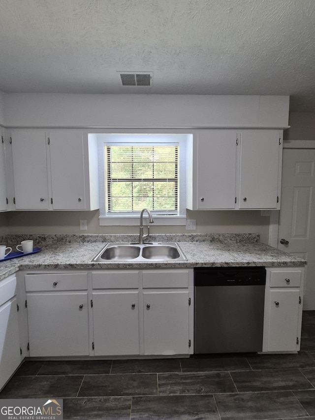 kitchen featuring stainless steel dishwasher, a sink, white cabinetry, and a textured ceiling
