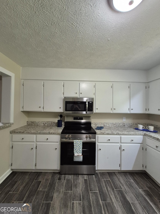 kitchen with stainless steel appliances, wood tiled floors, white cabinetry, light countertops, and a textured ceiling