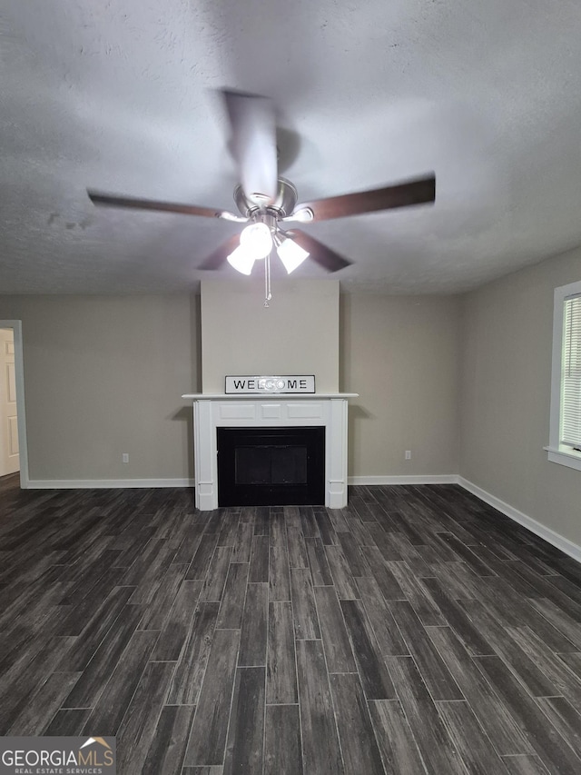 unfurnished living room featuring a fireplace, dark wood-type flooring, ceiling fan, and baseboards