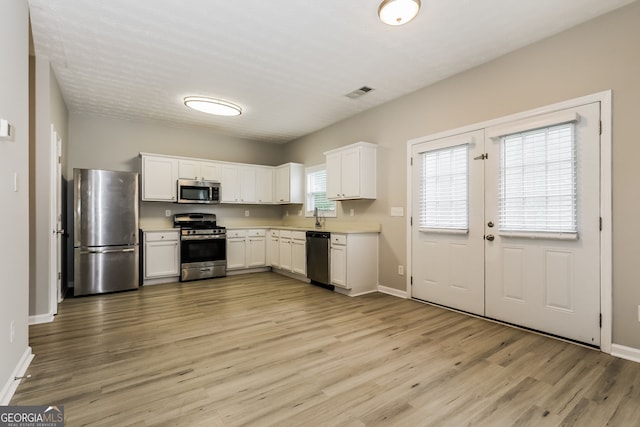 11576 Kades Trl, Hampton, GA 30228 - kitchen featuring appliances with stainless steel finishes, light wood-style floors, white cabinetry, and baseboards