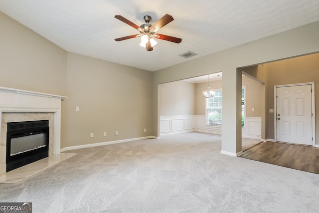 11576 Kades Trl, Hampton, GA 30228 - unfurnished living room with a premium fireplace, carpet flooring, a ceiling fan, a wainscoted wall, and a chandelier