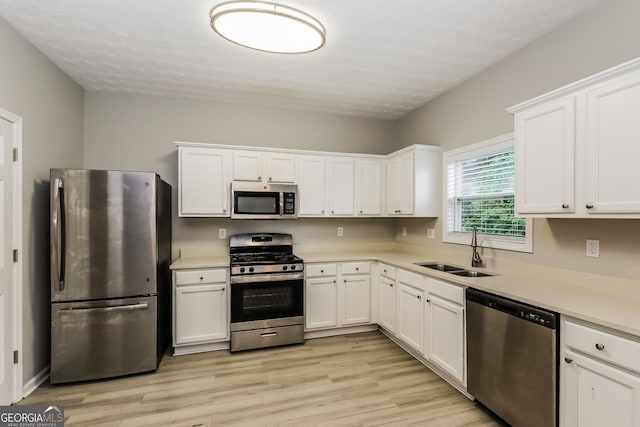 11576 Kades Trl, Hampton, GA 30228 - kitchen with appliances with stainless steel finishes, a sink, white cabinets, light wood-style flooring, and light countertops