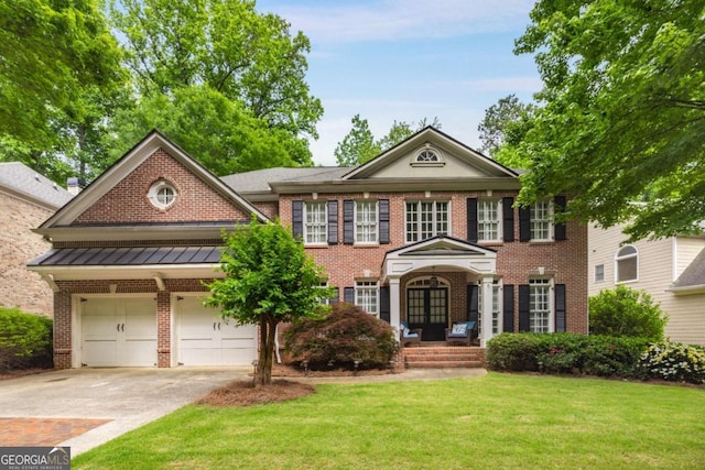 georgian-style home featuring driveway, brick siding, a front yard, and a standing seam roof