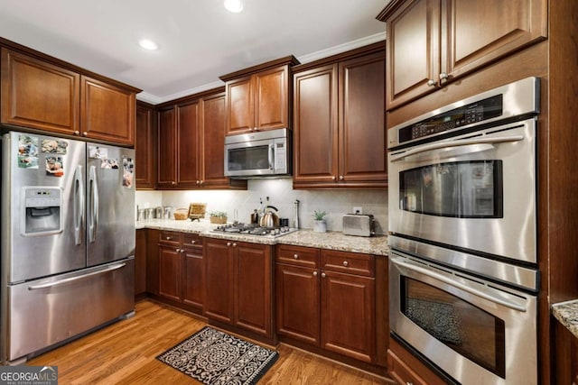 kitchen featuring stainless steel appliances, light wood-style flooring, light stone counters, recessed lighting, and tasteful backsplash