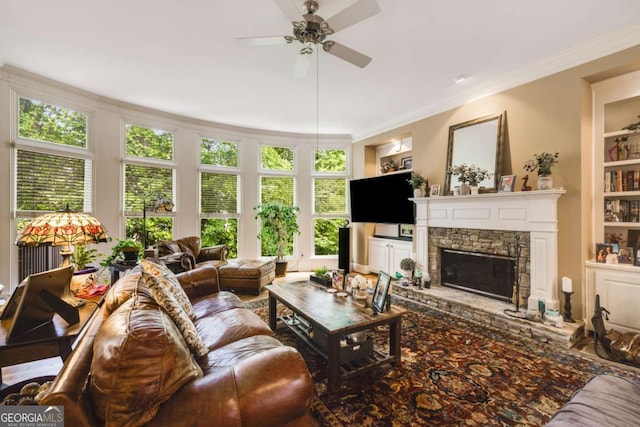 living area featuring built in features, ceiling fan, a fireplace, and ornamental molding