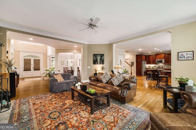 living room featuring a ceiling fan, light wood-style flooring, crown molding, decorative columns, and recessed lighting