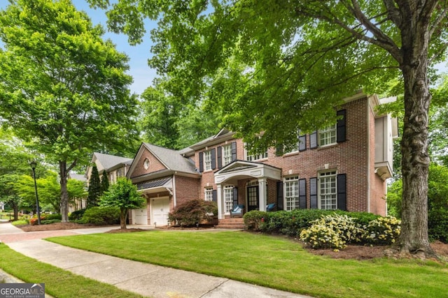 view of front of home with brick siding, a front yard, concrete driveway, and a garage