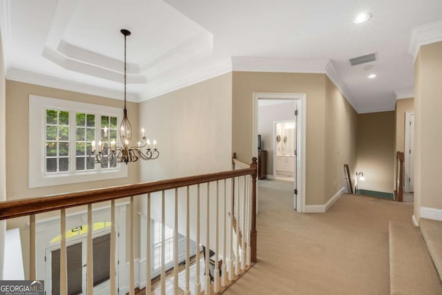 corridor with an upstairs landing, ornamental molding, light colored carpet, a chandelier, and baseboards