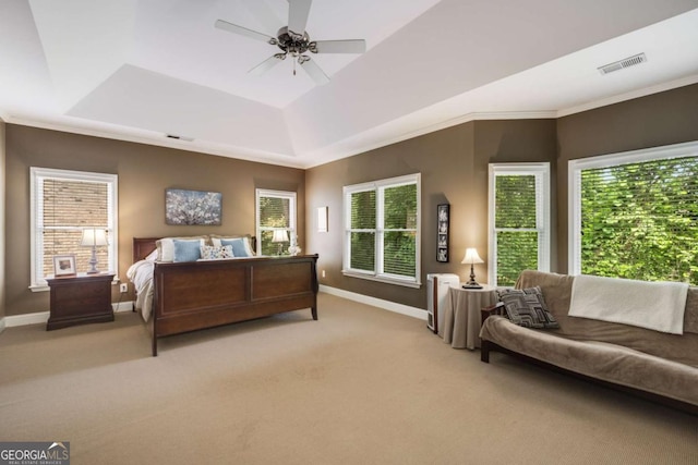 bedroom with a raised ceiling, baseboards, light colored carpet, ornamental molding, and a ceiling fan
