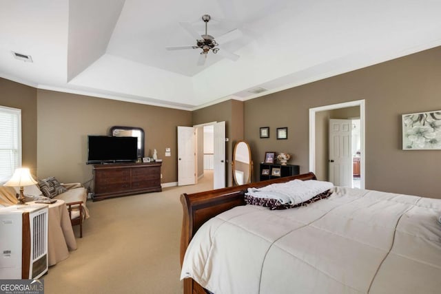 bedroom featuring light colored carpet, crown molding, a tray ceiling, and a ceiling fan