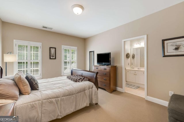 bedroom featuring light colored carpet, baseboards, connected bathroom, and a sink
