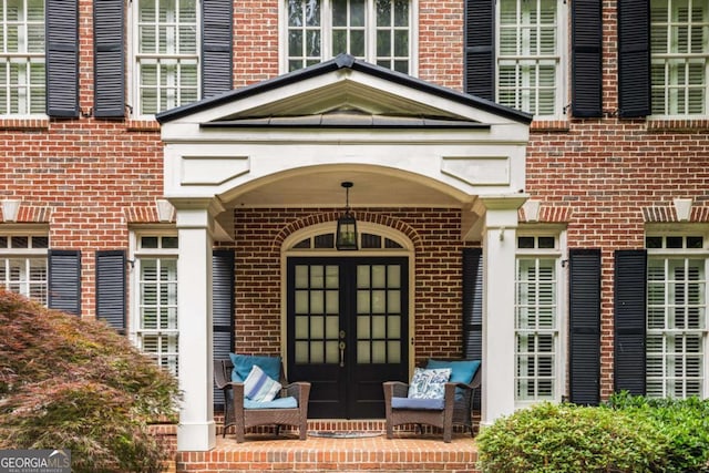 property entrance featuring french doors and brick siding