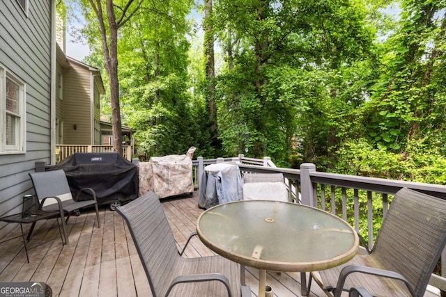 wooden terrace with outdoor dining area and area for grilling
