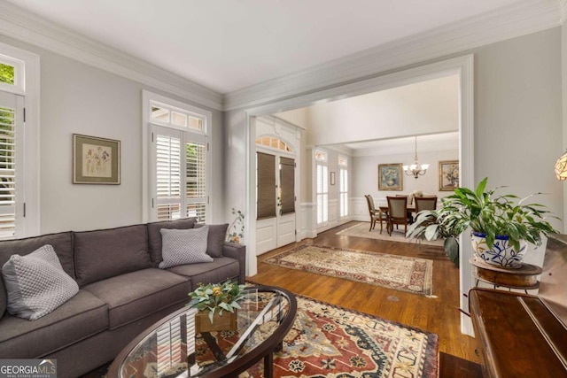 living area featuring wood finished floors, crown molding, a chandelier, and wainscoting