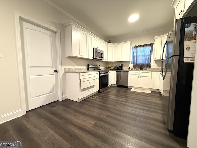 214 Evans St, Athens, GA 30606 - kitchen with appliances with stainless steel finishes, ornamental molding, white cabinetry, dark wood-style flooring, and light stone counters