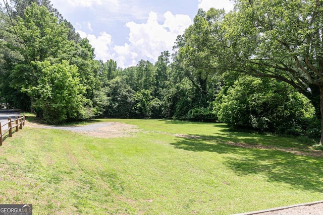 view of green lawn featuring a forest view