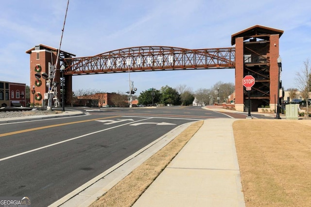 view of asphalt road featuring sidewalks, curbs, and traffic signs