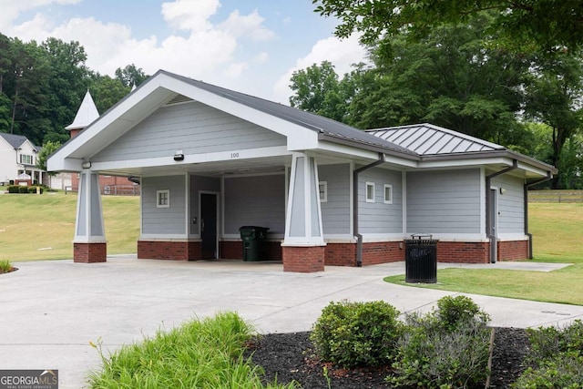 view of front of house featuring concrete driveway, a front lawn, a carport, a standing seam roof, and metal roof