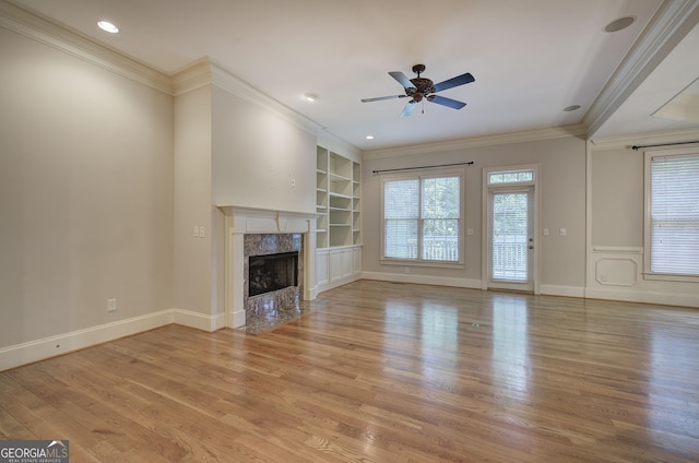 5492 Glenridge Dr Unit 536, Atlanta, GA 30342 - unfurnished living room featuring built in features, plenty of natural light, light wood finished floors, a fireplace, and crown molding
