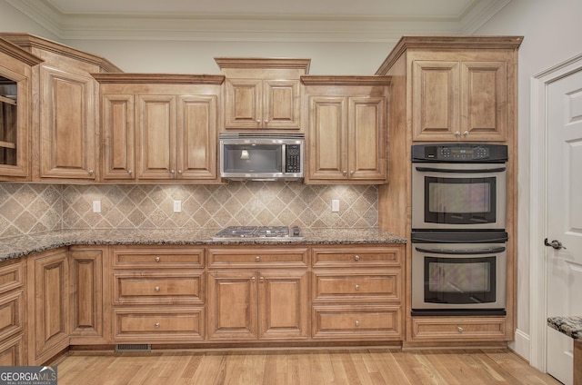 5492 Glenridge Dr Unit 536, Atlanta, GA 30342 - kitchen featuring stainless steel appliances, stone counters, backsplash, light wood-style flooring, and ornamental molding
