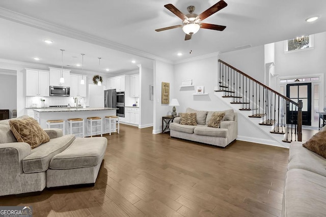 8745 Hightower Rdg, Ball Ground, GA 30107 - living area with a ceiling fan, stairs, dark wood-style flooring, recessed lighting, and ornamental molding