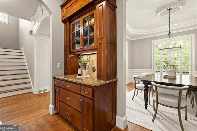 1286 Whisper Cove Dr, Buford, GA 30518 - bar featuring stairs, wood finished floors, a chandelier, decorative light fixtures, and crown molding
