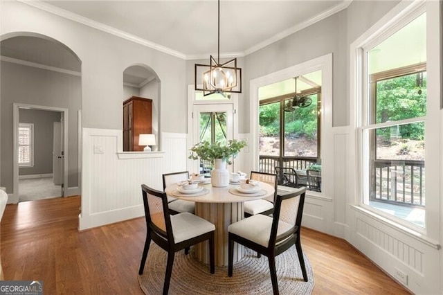 1286 Whisper Cove Dr, Buford, GA 30518 - dining area with a chandelier, a decorative wall, light wood-style flooring, arched walkways, and wainscoting