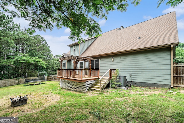 1235 Waterwood Dr, Loganville, GA 30052 - rear view of house featuring a trampoline, a deck, a pergola, a fenced backyard, and a fire pit