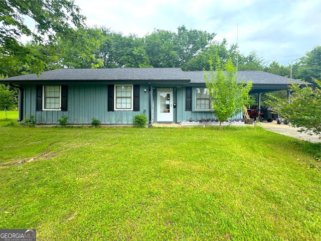 single story home with board and batten siding, a carport, and a front lawn