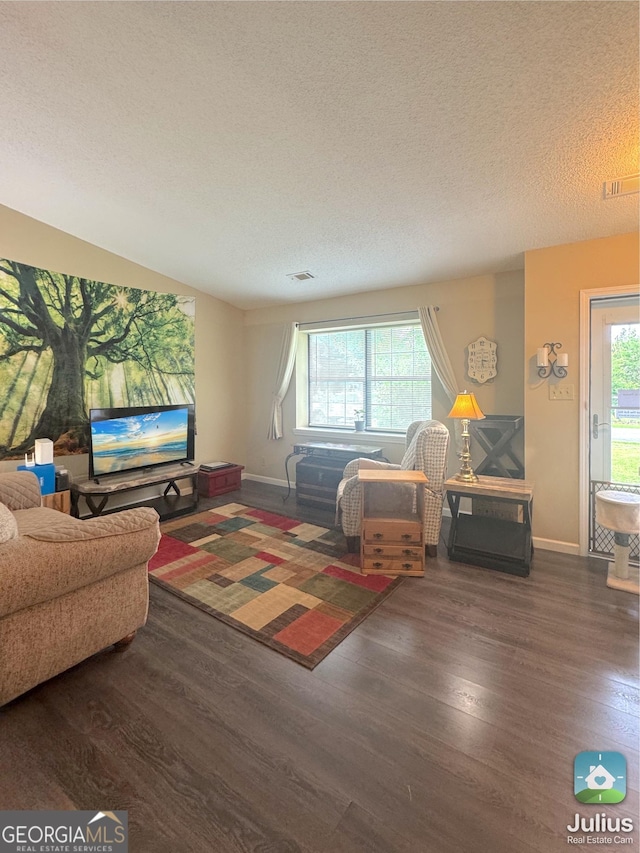 living area with wood finished floors, healthy amount of natural light, baseboards, and a textured ceiling