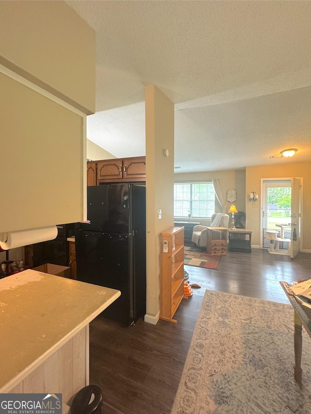 kitchen with freestanding refrigerator, a textured ceiling, plenty of natural light, dark wood finished floors, and open floor plan