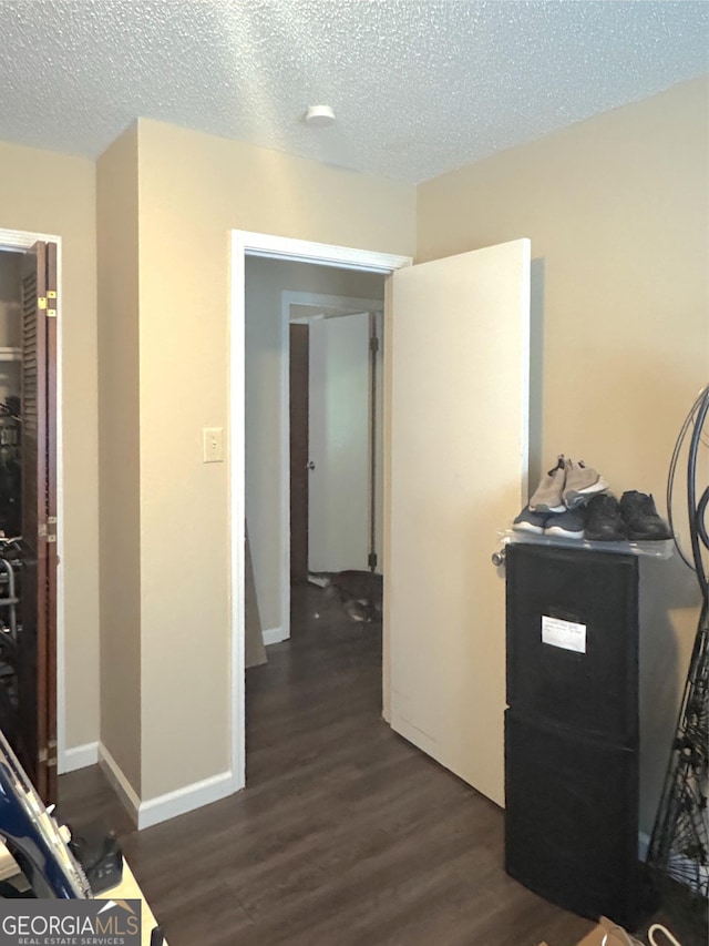 hall featuring dark wood-type flooring and a textured ceiling