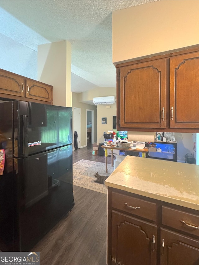 kitchen featuring freestanding refrigerator, a textured ceiling, dark wood finished floors, lofted ceiling, and light countertops