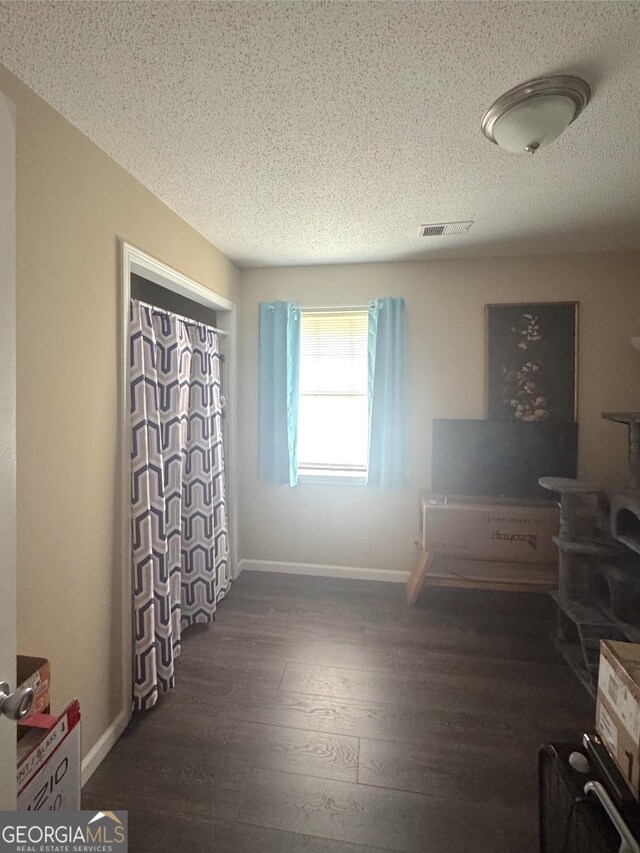 bedroom with dark wood-style floors, a textured ceiling, and baseboards