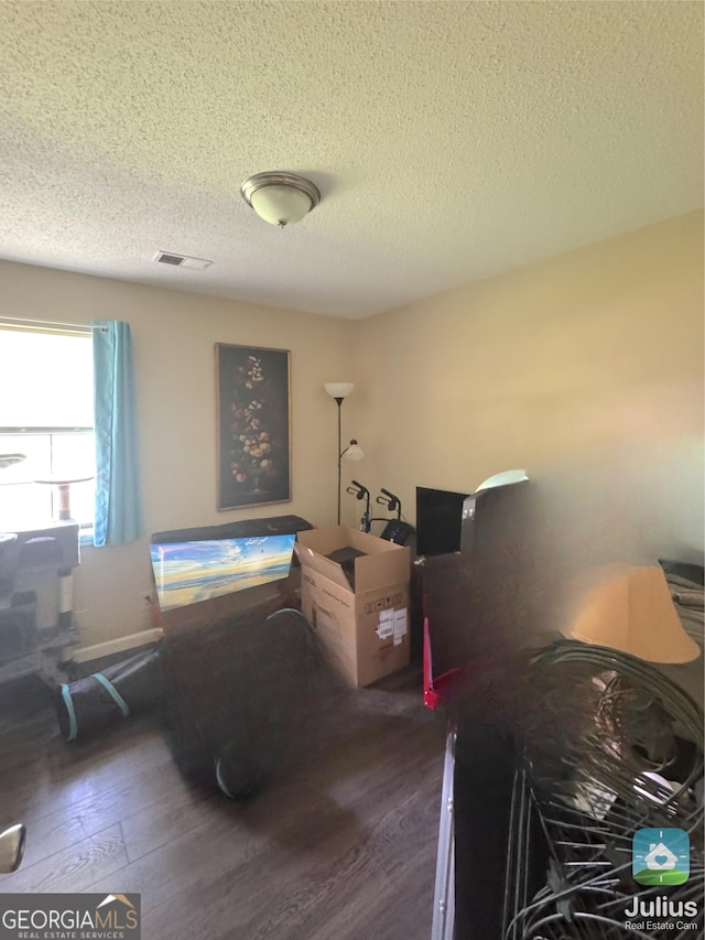 misc room with dark wood-type flooring and a textured ceiling