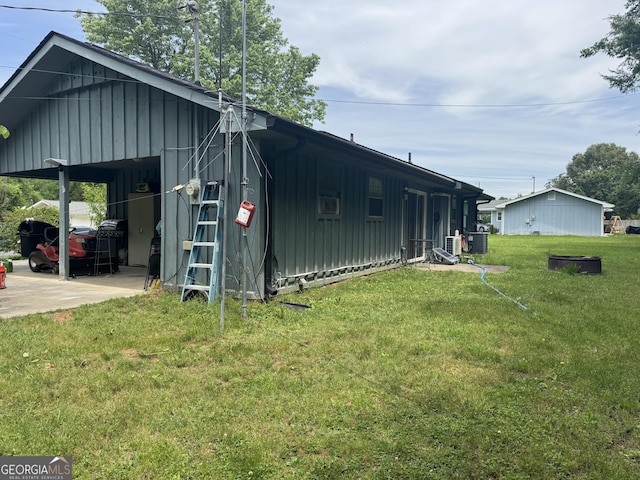 view of side of property featuring board and batten siding, an attached carport, a yard, and central air condition unit