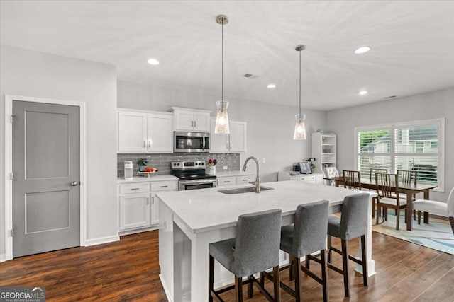 123 Cedar Park Way, Carrollton, GA 30117 - kitchen with stainless steel appliances, a sink, dark wood-style flooring, light countertops, and a breakfast bar