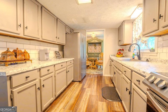 5293 Sandy Shoals Ln, Stone Mountain, GA 30087 - kitchen featuring appliances with stainless steel finishes, light wood finished floors, a textured ceiling, a sink, and backsplash