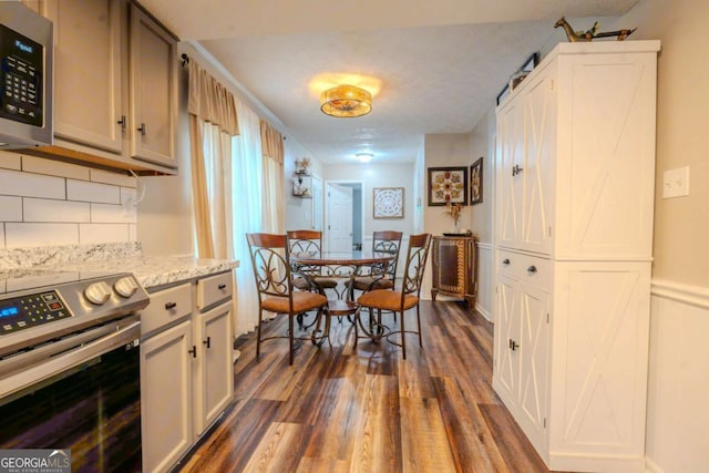 5293 Sandy Shoals Ln, Stone Mountain, GA 30087 - kitchen featuring appliances with stainless steel finishes, dark wood-type flooring, decorative backsplash, and light stone countertops
