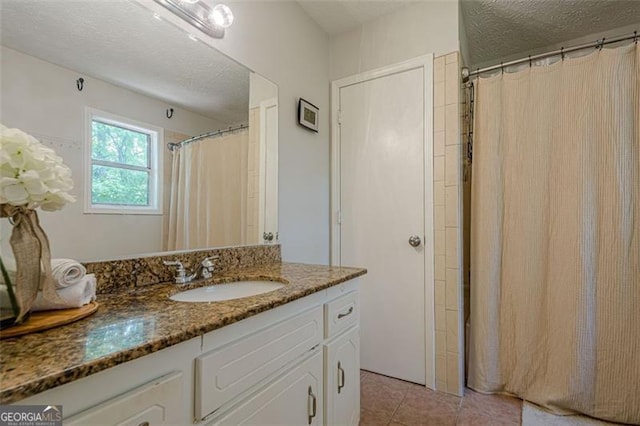 full bath featuring a textured ceiling, tile patterned floors, vanity, and curtained shower