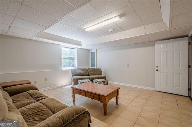 living area featuring baseboards, a paneled ceiling, and light tile patterned floors