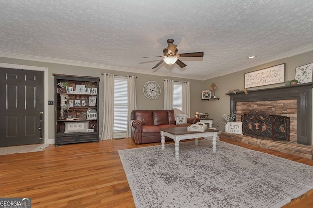 9001 E Carroll Rd, Winston, GA 30187 - living room with light wood-style flooring, a ceiling fan, a textured ceiling, ornamental molding, and a stone fireplace