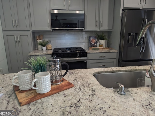 921 Oak Dr, Woodstock, GA 30189 - kitchen featuring stainless steel fridge with ice dispenser, black gas stove, gray cabinets, light stone counters, and tasteful backsplash